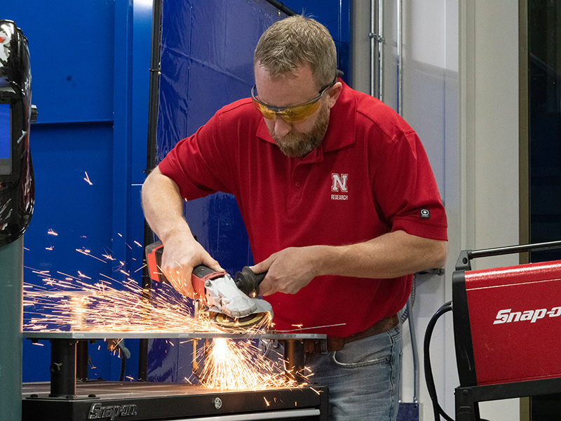 Instructor using grinder tool as sparks fly